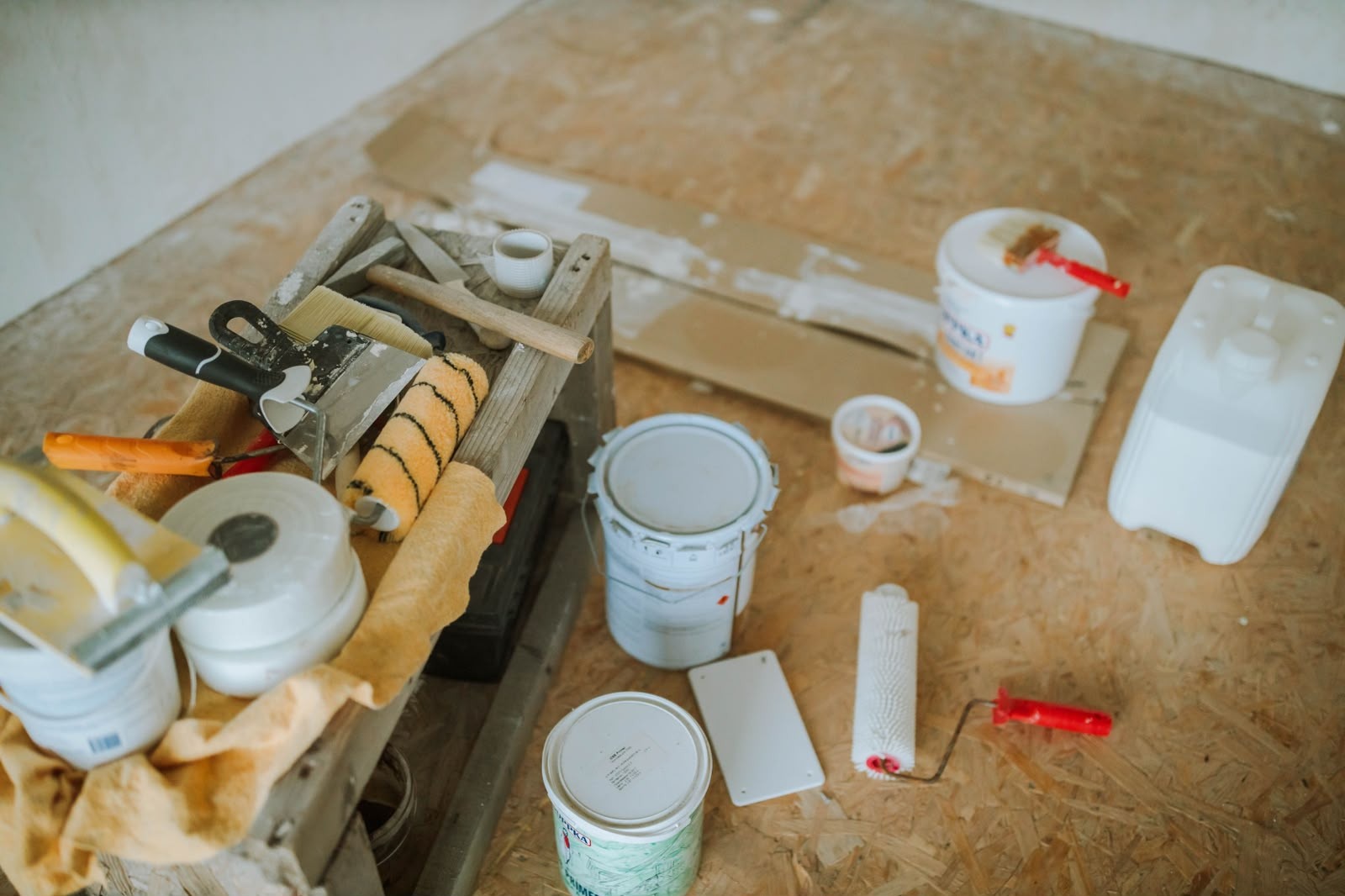Decorator's tools laid out on a dust sheet — fillers, scrapers, rollers and paint tins