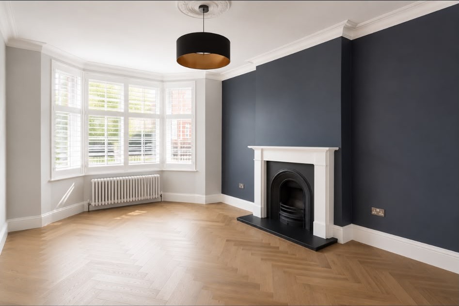 Freshly painted living room with a deep navy feature wall, white cornice and herringbone floor
